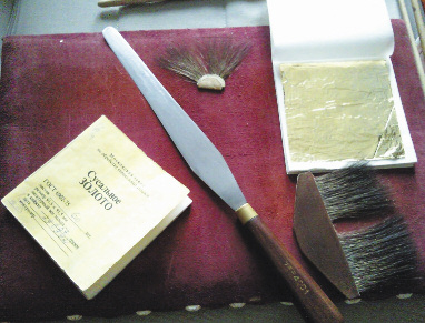 Инструментарий позолотчика: специальный нож для резки золота, замшевая подушка, на которой происходит вся предварительная обработка золота, «лапки»